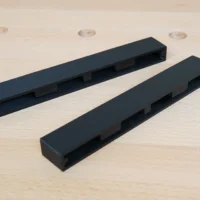 Two black protective caps for Ryobi track saw rails, showing rectangular channel design for friction fit mounting