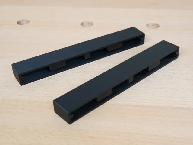 Two black protective caps for Ryobi track saw rails, showing rectangular channel design for friction fit mounting