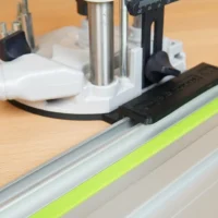 Black ToolCurve adapter mounted on Festool guide rail, attached to OF 1010 router base above the rail