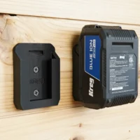 Black Kreg battery mount attached to wood wall next to a Kreg 18v Blue Lion battery, showing slot for battery to click into place