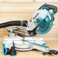 Black 2-1/2 inch ToolCurve hose adapter installed on a Makita LS miter saw dust port, with a spare adapter on the bench