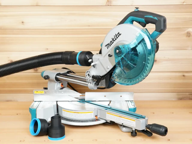 Black 2-1/2 inch ToolCurve hose adapter installed on a Makita LS miter saw dust port, with a spare adapter on the bench