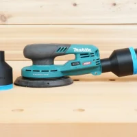 Black 2-1/2 inch hose adapter with blue band installed on a Makita XGT sander, second adapter beside it