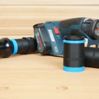Two black 1-1/4" hose adapters with blue knurled ends beside a Bosch 12V MAX planer and orange hose