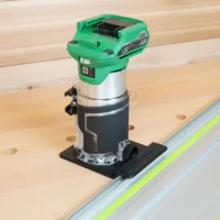 Metabo HPT 18V cordless trim router mounted on a rail adapter, positioned on a Festool-style guide rail over wooden workpiece
