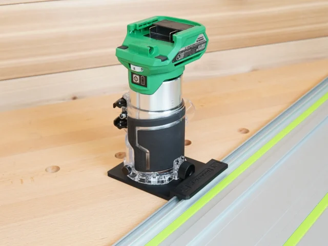Metabo HPT 18V cordless trim router mounted on a rail adapter, positioned on a Festool-style guide rail over wooden workpiece