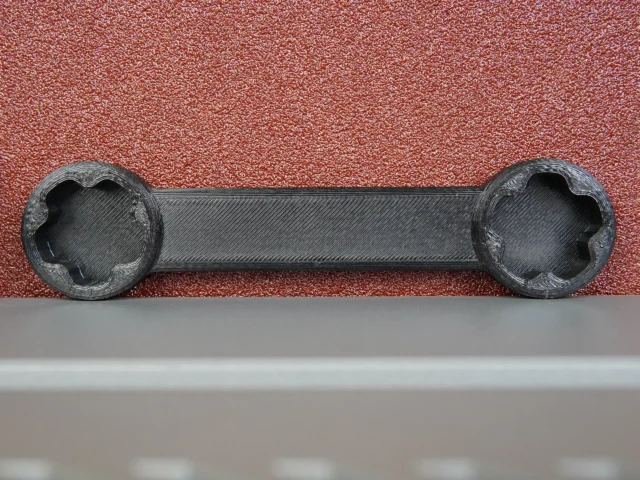 Black 3D-printed wrench with four-pointed sockets on each end, designed to fit Ridgid sander adjustment knobs