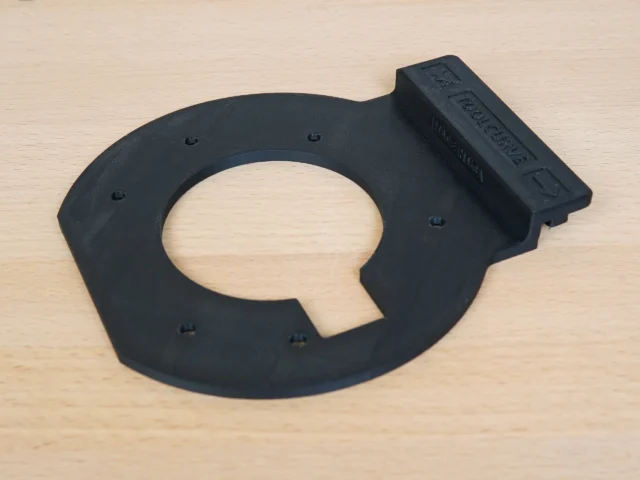 Black 3D-printed guide rail adapter for Festool OF 1010 router with central oval opening and mounting holes