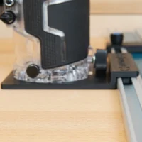 Black plastic rail adapter mounted on Metabo HPT cordless trim router, seated on an aluminum guide rail