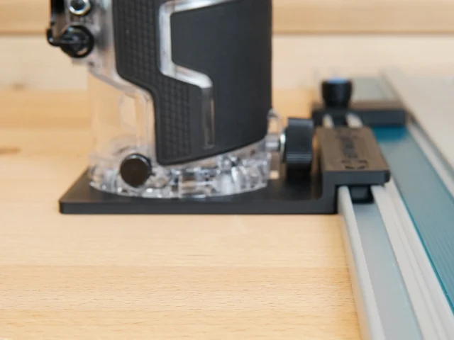 Black plastic rail adapter mounted on Metabo HPT cordless trim router, seated on an aluminum guide rail
