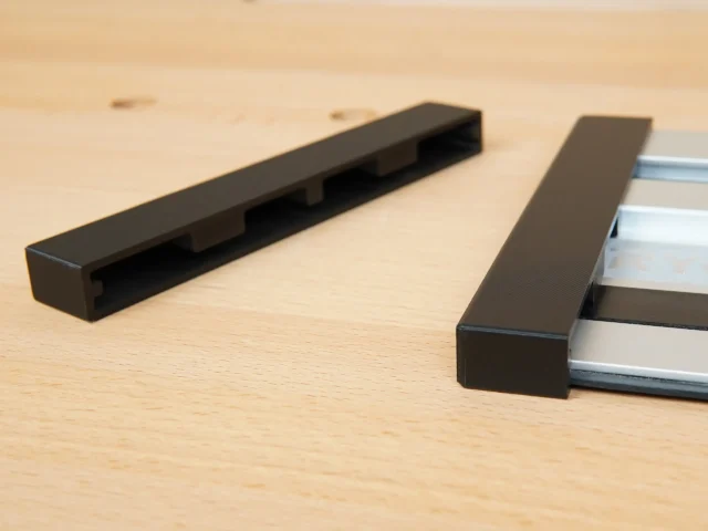 Two black protective caps shown separately and one installed on an aluminum Ryobi track saw rail, displaying the friction-fit design