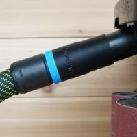 Black hose adapter with blue grip band marked ToolCurve, connected to green braided dust extraction hose on WEN oscillating spindle sander