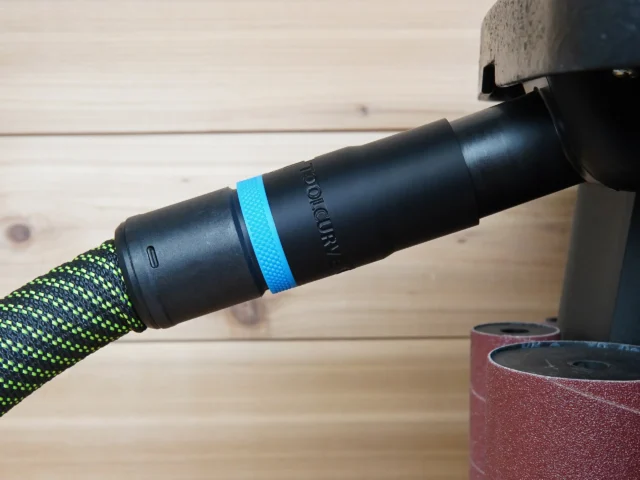 Black hose adapter with blue grip band marked ToolCurve, connected to green braided dust extraction hose on WEN oscillating spindle sander