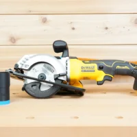 Black ToolCurve 1-1/4 inch hose adapter with blue trim resting beside a Dewalt Atomic 20V 4-1/2 in. circular saw