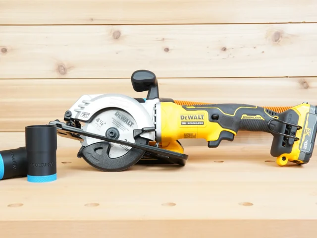 Black ToolCurve 1-1/4 inch hose adapter with blue trim resting beside a Dewalt Atomic 20V 4-1/2 in. circular saw