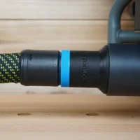 Black hose adapter with blue band attached to braided green and black hose at Craftsman table saw dust port