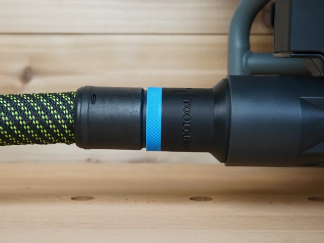 Black hose adapter with blue band attached to braided green and black hose at Craftsman table saw dust port