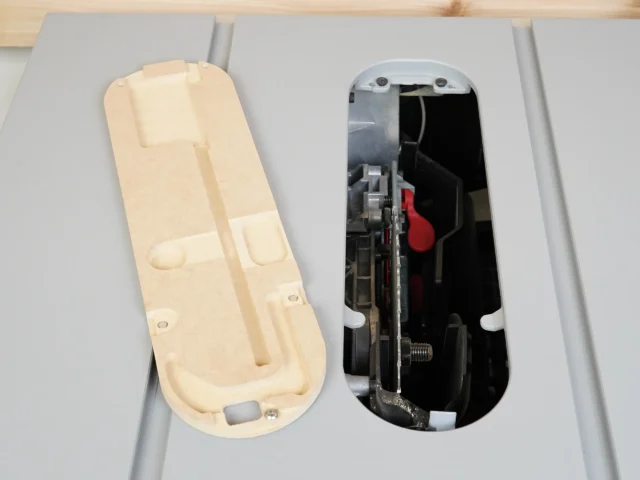 Beige MDF zero clearance insert shown from above alongside the metal SawStop Jobsite PRO table saw insert it replaces, revealing internal mechanism and red trigger component