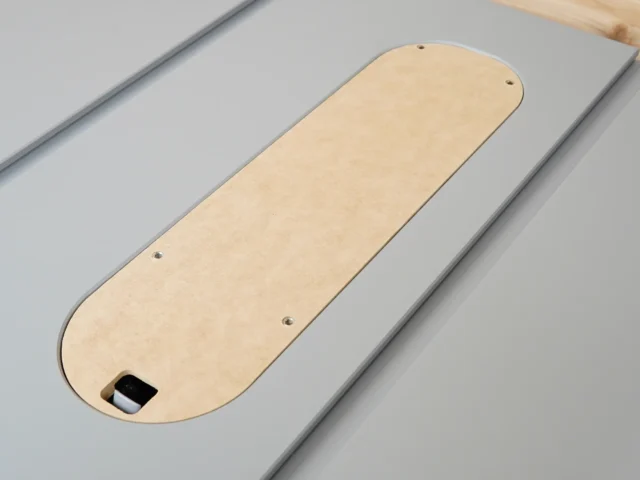 Birch zero clearance insert for SawStop table saw, showing rounded end with mounting holes and recessed blade slot