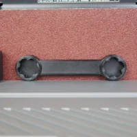 Black 3D-printed wrench with two round sockets on ends, shown above a red sanding belt on a Ridgid sander