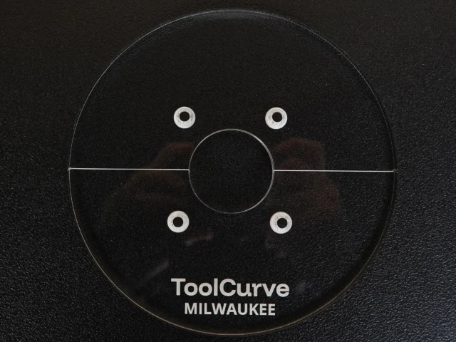 Black acrylic circular router base plate with center hole and four mounting holes, labeled ToolCurve Milwaukee