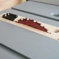 MDF zero clearance insert installed in a gray Ridgid table saw with red blade and riving knife through the slot
