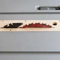 Light wood zero clearance insert for Ridgid table saw, showing black and red saw blade profiles cut through the center, mounted on saw table