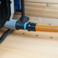 Black 1-1/4 inch hose adapter with blue ring joining an orange shop vac hose to a Hercules table saw dust port
