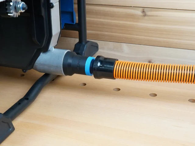 Black 1-1/4 inch hose adapter with blue ring joining an orange shop vac hose to a Hercules table saw dust port