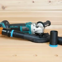 Black 1-1/4 inch hose adapter with blue trim linking an orange hose to a Makita grinding shroud, two spare adapters beside it