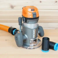Ridgid 2 HP fixed base router with orange hose attached, plus two black ToolCurve 1-1/4" hose adapters beside it