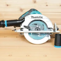Black 1-1/4" ToolCurve hose adapter linking an orange hose to a Makita 7-1/4" circular saw, spare adapters beside