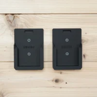 Two black Ridgid battery mounts mounted on a light wood wall, each with a recessed slot and Phillips head screws visible