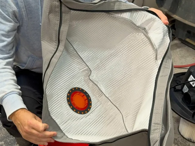 Macam reusable dust bag with red and orange circular inlet seal, held open to show white polyester interior lining