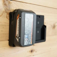 Black plastic battery mount holding a Ridgid 18v lithium-ion battery on a wooden wall
