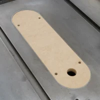Beige MDF zero clearance insert for Delta Unisaw X5 table saw, with rounded ends and three mounting holes, shown on metal table saw surface