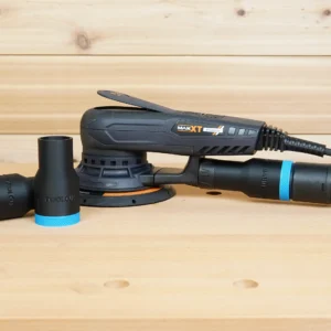 Black ToolCurve hose adapters with blue rings resting beside a MAXXT random orbital sander, one adapter joining a green extractor hose to the sander's rear port
