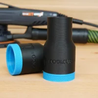 Black ToolCurve hose adapter with blue grip ring, shown with matching smaller adapter component on wooden surface behind a Festool sander
