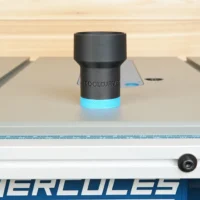 Black cylindrical hose adapter with blue grip band, mounted on a Hercules table saw dust port