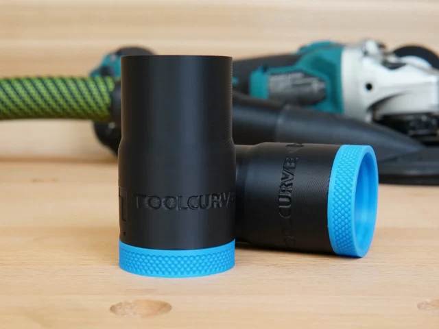 Black ToolCurve hose adapter with blue textured grip band, shown with matching adapter and Makita grinder in background