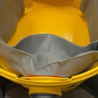 Macam reusable dust bag for DeWalt shop vacs shown inside yellow plastic housing, gray fabric interior with elastic opening visible