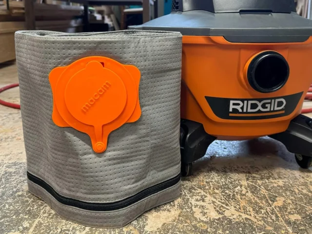 Macam reusable dust bag in tan polyester with orange plastic cap, shown next to a Ridgid shop-vac for size comparison