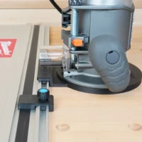 Guide rail adapter mounted on a Ridgid 2 HP router, attached to a Festool track saw rail on a wooden workbench