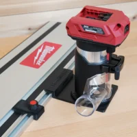 SKIL 20v trim router mounted on black guide rail adapter, attached to track saw rail on wooden workbench