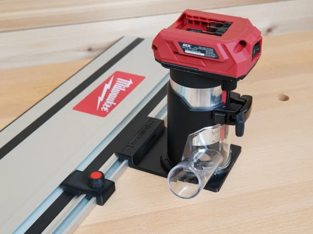 SKIL 20v trim router mounted on black guide rail adapter, attached to track saw rail on wooden workbench