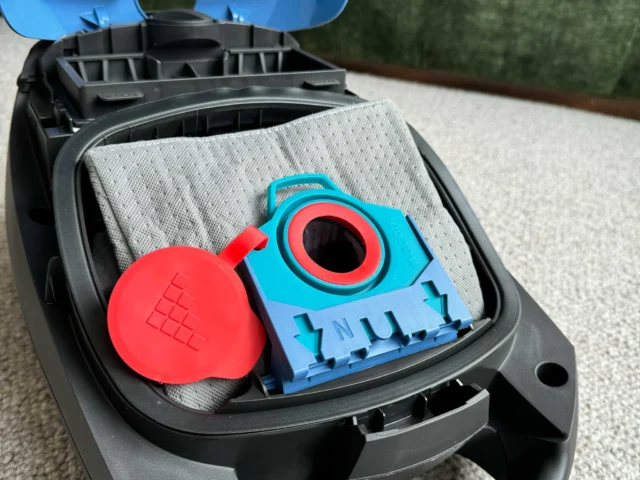Macam reusable dust bag in blue and red inside open Miele vacuum canister, with red cap and gray filter visible