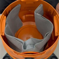 Orange dust bag with gray polyester interior and elastic opening, shown open and held by two hands, revealing inner chamber and rigid plastic base