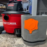 Gray Macam reusable dust bag with orange top cap, positioned next to a red Craftsman shop-vac