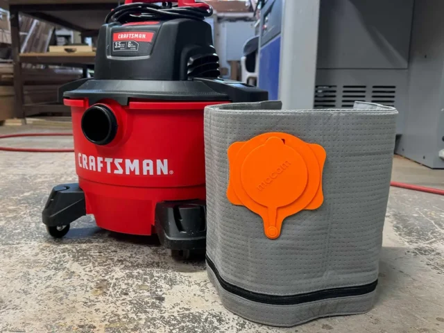 Gray Macam reusable dust bag with orange top cap, positioned next to a red Craftsman shop-vac