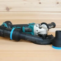 Black 2-1/2 inch ToolCurve hose adapter on Makita XAG04 grinder shroud, second adapter shown beside it